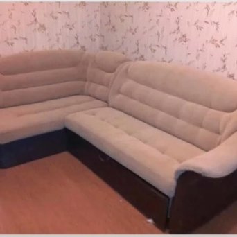В углу комнаты стоит бежевый, угловой диван с обивкой из бежевого велюра. Диван выглядит новым, после того, как Мастерская Мебели48 произвела ремонт данного дивана.