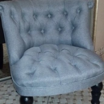 Кресло после недорого ремонта, сделанном Мастерской Мебели 48. Сине-серого цвета. Стоит на полу, уложенном кафельной плиткой.